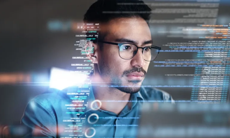 Person with glasses looking at computer screen with code and digital interface elements overlaid