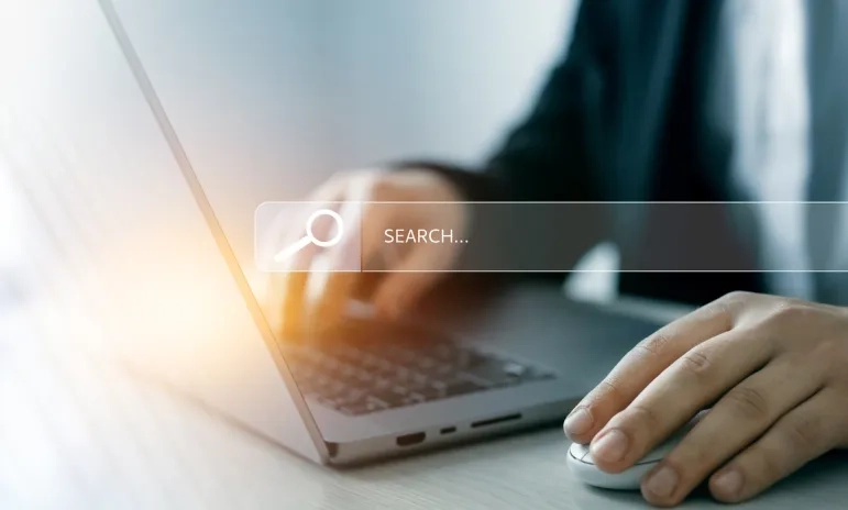Person using a laptop and mouse with a search bar overlay, representing website navigation.