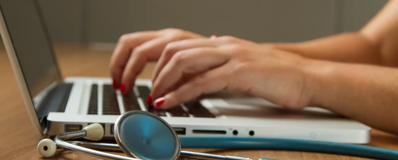 person writing at laptop