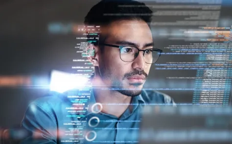 Person with glasses looking at computer screen with code and digital interface elements overlaid
